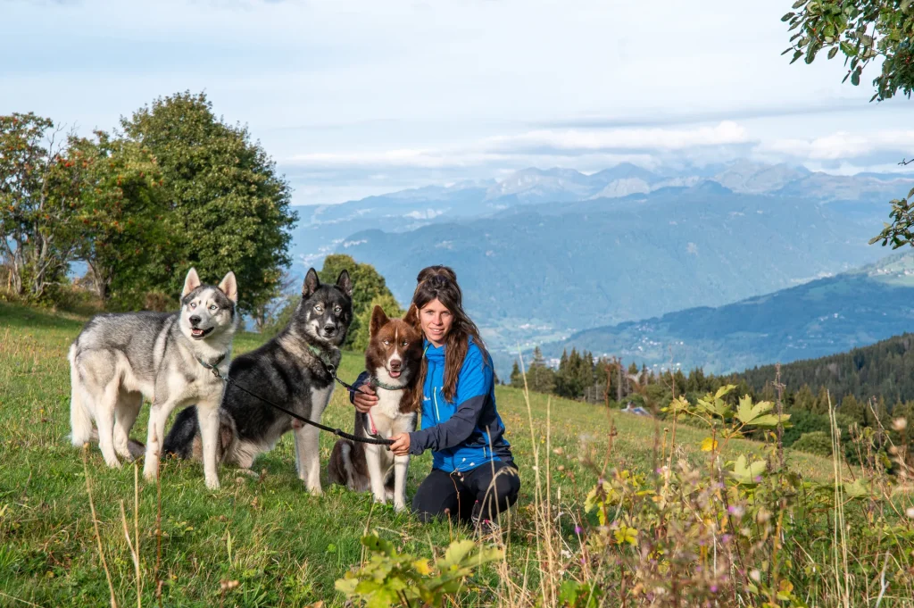 Élodie Martin entourée de ses chiens de traineaux dans un champs à Mont-Saxonnex