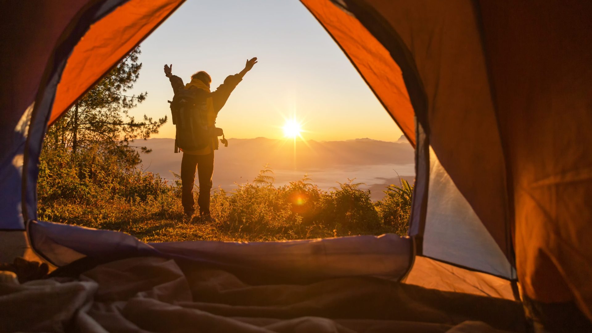 Campeur profitant d'un lever de soleil. Vue depuis la tente