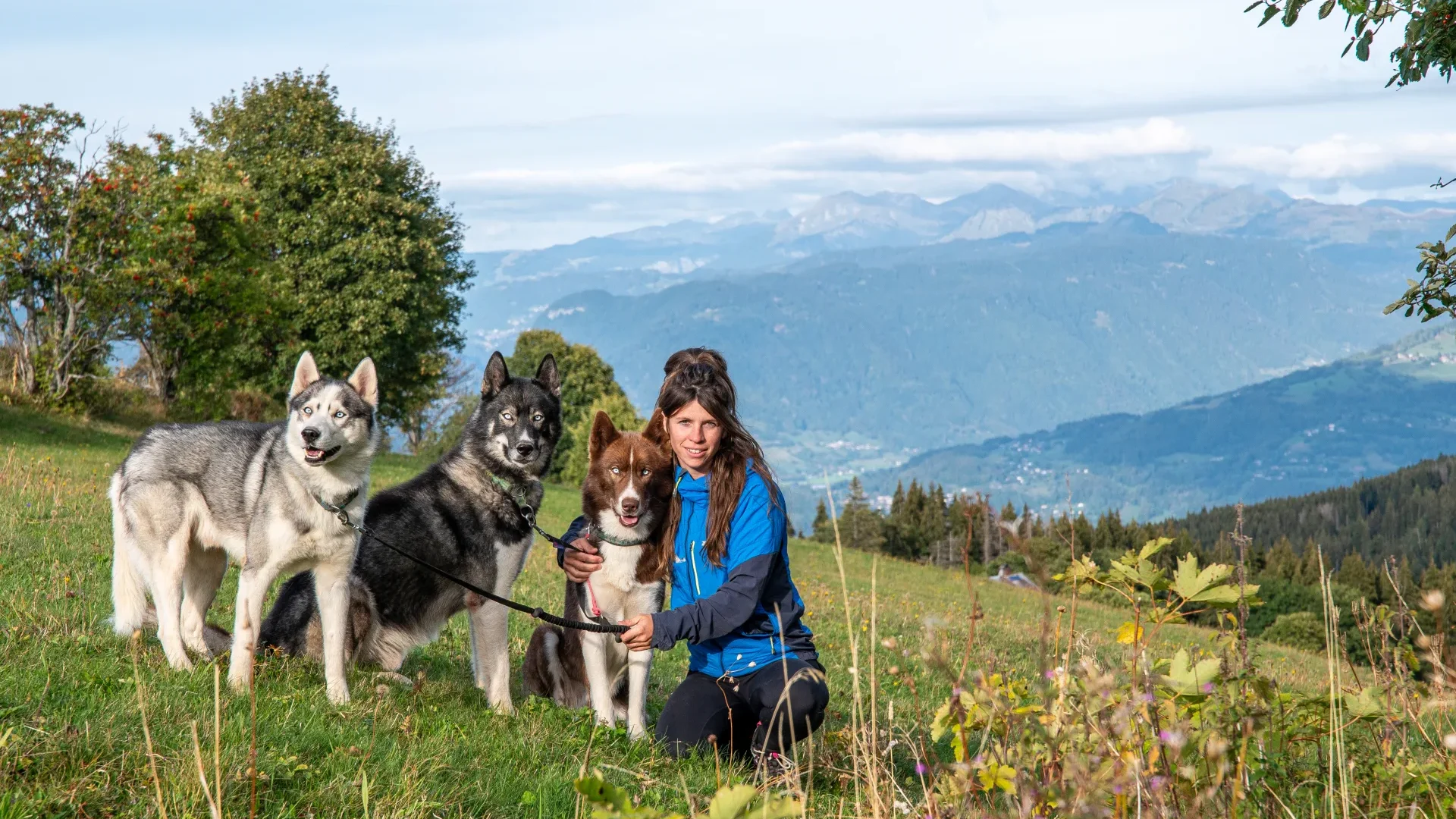 Élodie Martin entourée de ses chiens de traineaux dans un champs à Mont-Saxonnex