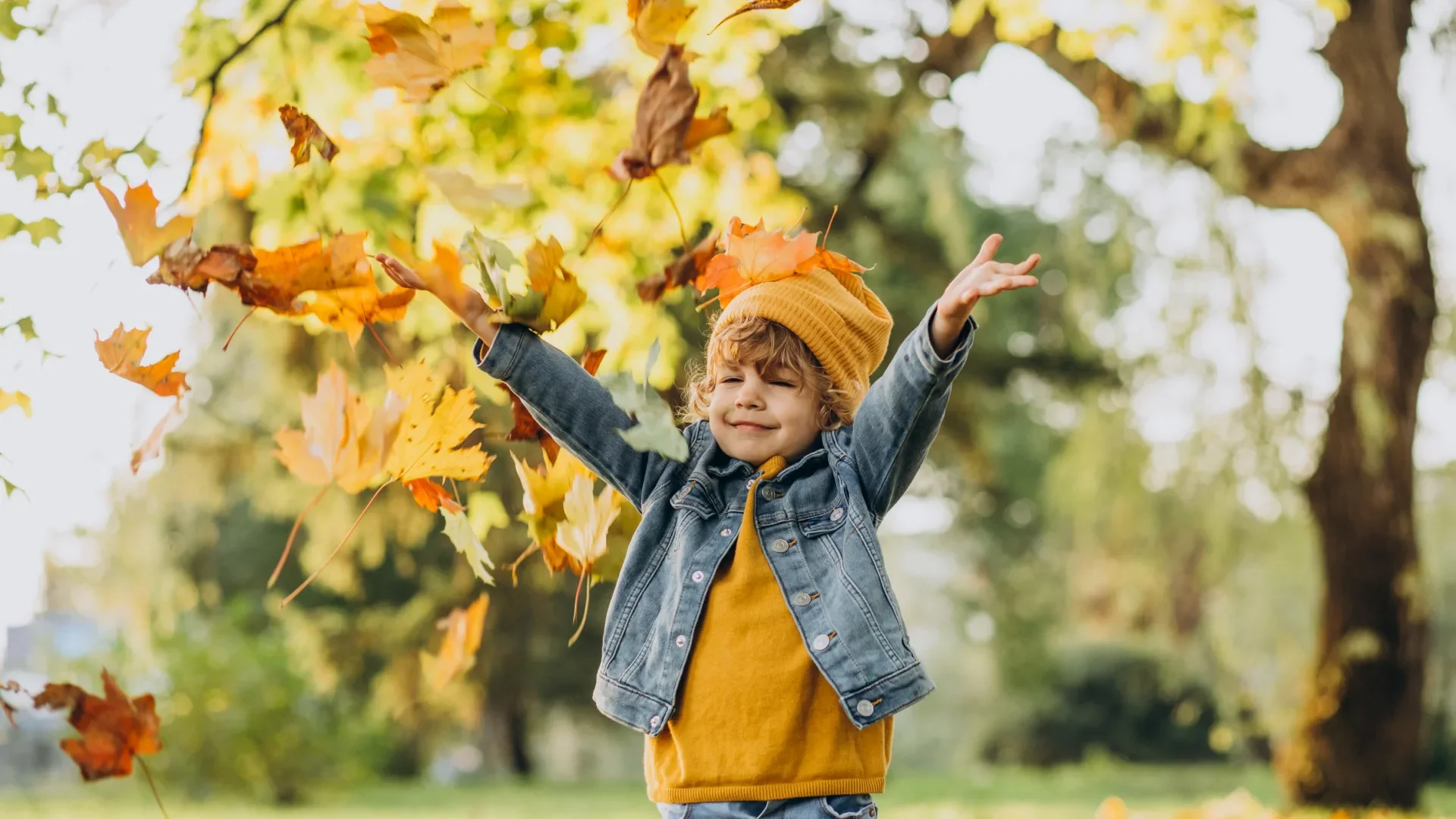 Enfant qui joue dans les feuilles d'automne