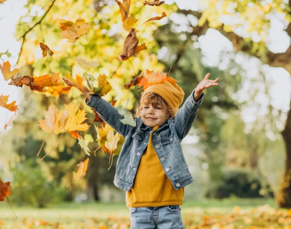 Enfant qui joue dans les feuilles d'automne